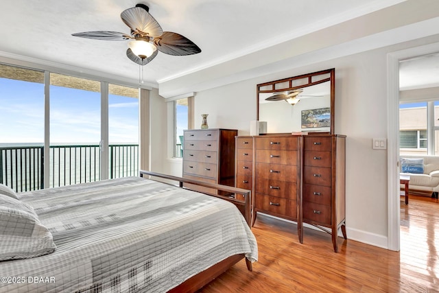 bedroom featuring ceiling fan, multiple windows, access to outside, and a water view