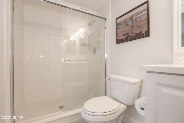 bathroom featuring toilet, a shower with shower door, and vanity