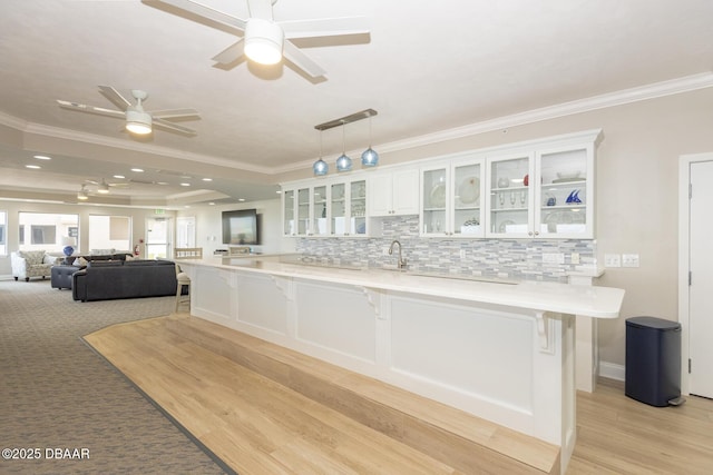 kitchen featuring ceiling fan, a kitchen breakfast bar, white cabinetry, and ornamental molding