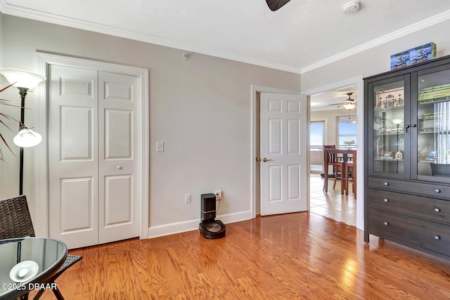 interior space with light wood-type flooring, ceiling fan, ornamental molding, and a closet