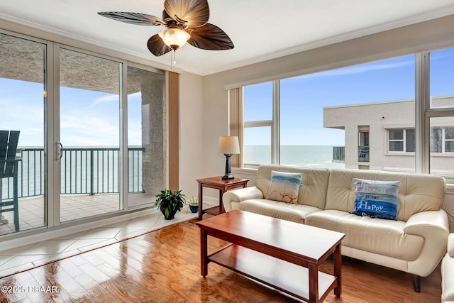 living room featuring hardwood / wood-style flooring, a water view, ornamental molding, and plenty of natural light