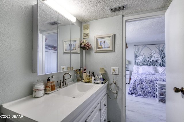 bathroom with hardwood / wood-style flooring, vanity, and a textured ceiling