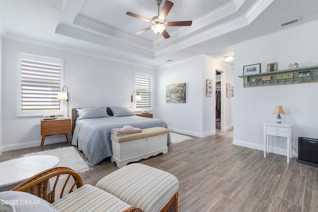 bedroom featuring crown molding, a tray ceiling, and light wood-type flooring