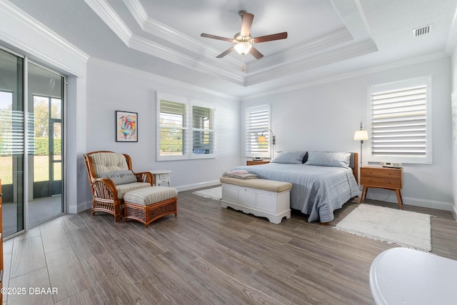 bedroom with crown molding, a tray ceiling, access to outside, and hardwood / wood-style flooring