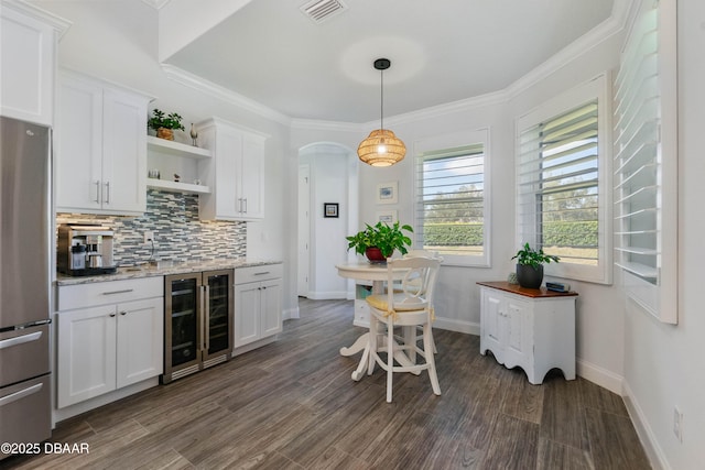 kitchen with stainless steel fridge, wine cooler, light stone counters, tasteful backsplash, and white cabinets