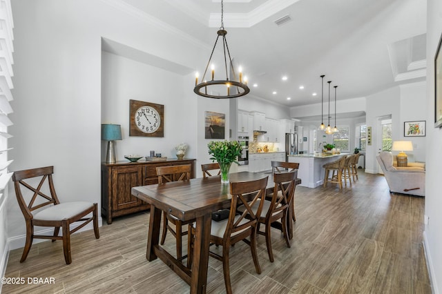 dining space with ornamental molding, light wood-type flooring, and a notable chandelier