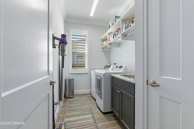 laundry room featuring dark wood-type flooring, cabinets, crown molding, and washer and clothes dryer