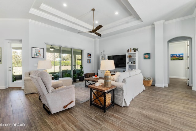 living room featuring hardwood / wood-style flooring, ceiling fan, a tray ceiling, and crown molding