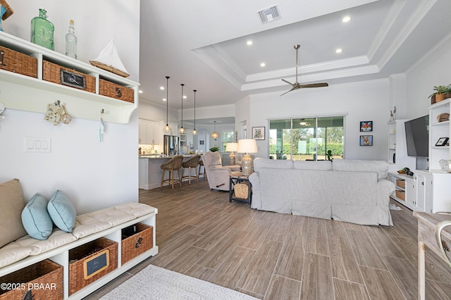 living room featuring crown molding, a towering ceiling, a raised ceiling, and ceiling fan