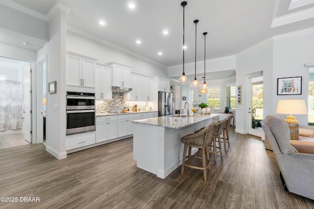 kitchen featuring appliances with stainless steel finishes, a breakfast bar, an island with sink, and white cabinets