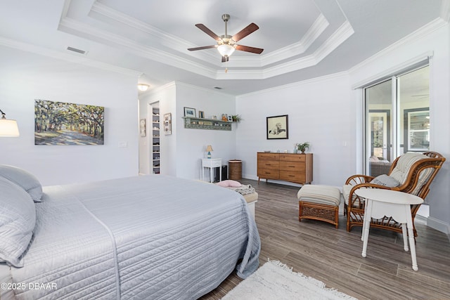 bedroom with ornamental molding, a tray ceiling, dark hardwood / wood-style flooring, and access to exterior