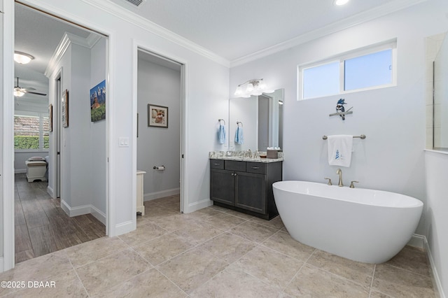 bathroom with crown molding, a washtub, vanity, and ceiling fan