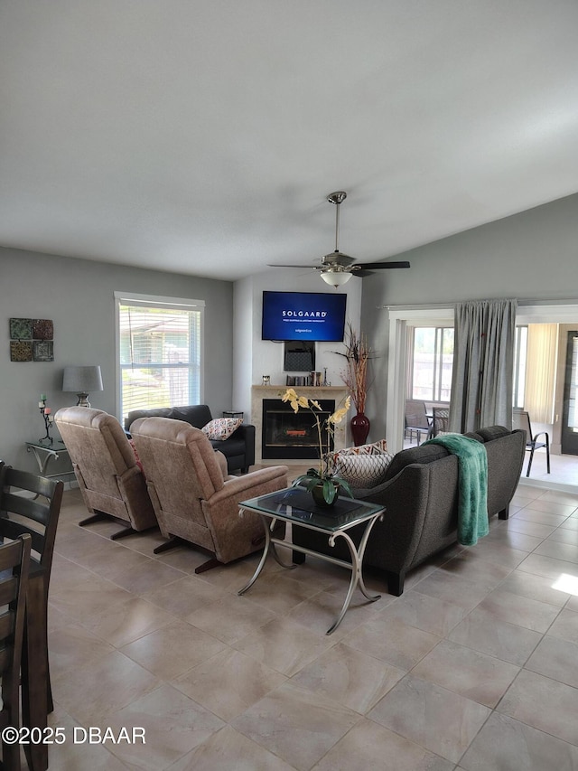living area featuring ceiling fan, light tile patterned floors, and a glass covered fireplace