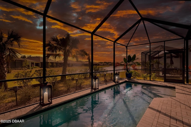 pool at dusk with a lanai and a patio area