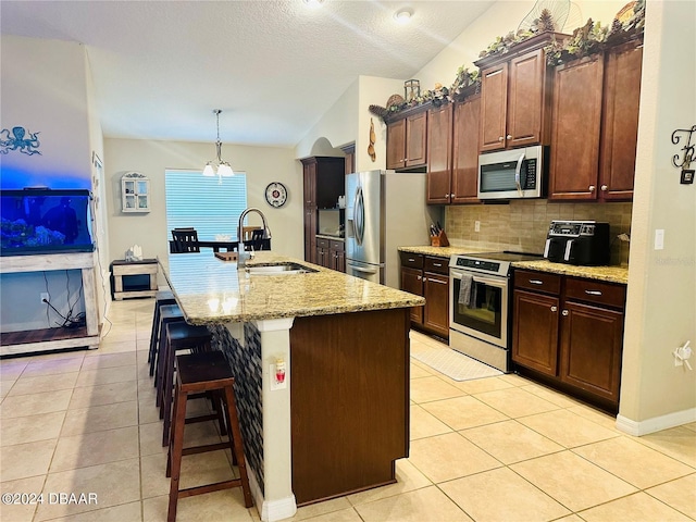 kitchen with a center island with sink, appliances with stainless steel finishes, a kitchen bar, sink, and lofted ceiling