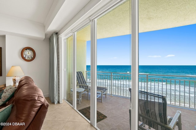 doorway to outside with a view of the beach, a water view, and light tile patterned flooring