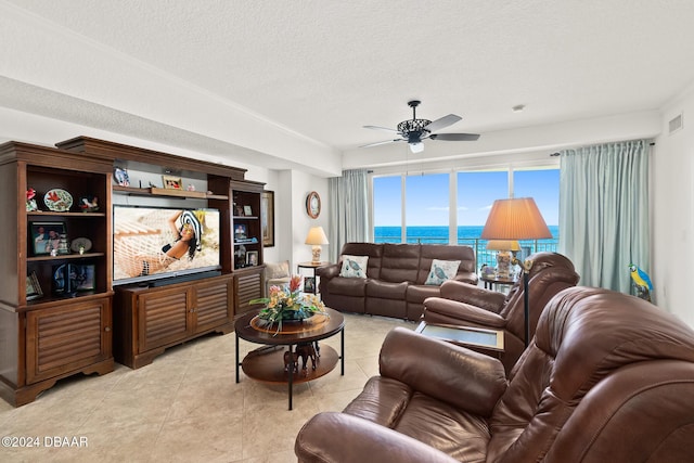 tiled living room with ceiling fan and a textured ceiling