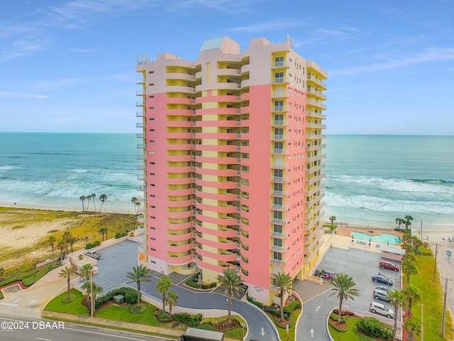 view of building exterior featuring a water view and a view of the beach