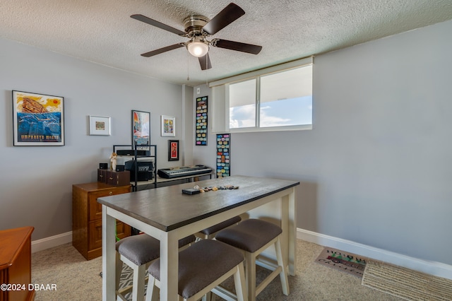 carpeted office space with a textured ceiling and ceiling fan