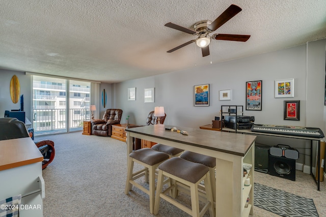 kitchen with light carpet, a textured ceiling, a kitchen bar, and ceiling fan