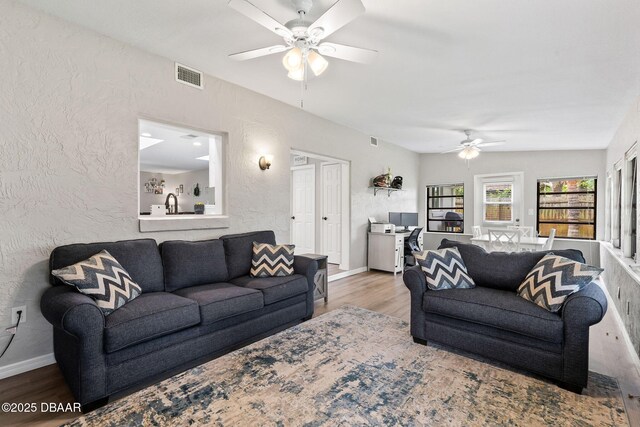 1317 Dexter Dr W, Port Orange, FL 32129 - living area with a ceiling fan, wood finished floors, a textured wall, and baseboards