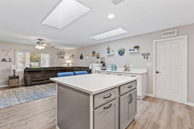 1317 Dexter Dr W, Port Orange, FL 32129 - kitchen featuring a skylight, light wood finished floors, light countertops, a center island, and recessed lighting