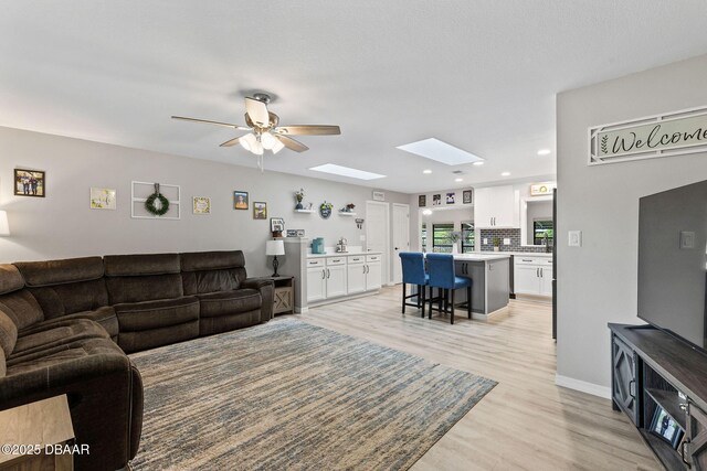 1317 Dexter Dr W, Port Orange, FL 32129 - living area with a skylight, light wood finished floors, ceiling fan, recessed lighting, and baseboards