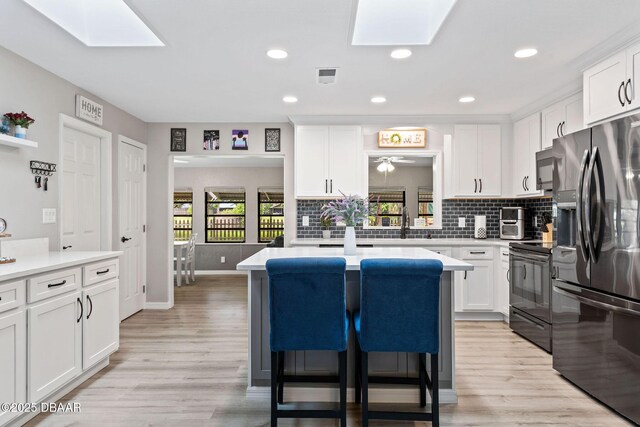 1317 Dexter Dr W, Port Orange, FL 32129 - kitchen featuring stainless steel fridge with ice dispenser, a skylight, black range with electric stovetop, light countertops, and recessed lighting
