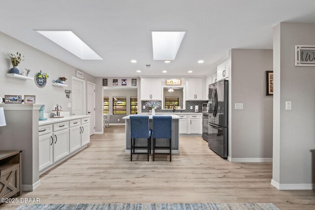 1317 Dexter Dr W, Port Orange, FL 32129 - kitchen with refrigerator with ice dispenser, a skylight, white cabinetry, and recessed lighting