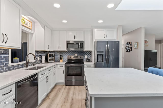 1317 Dexter Dr W, Port Orange, FL 32129 - kitchen with stainless steel appliances, a sink, light wood finished floors, white cabinetry, and tasteful backsplash