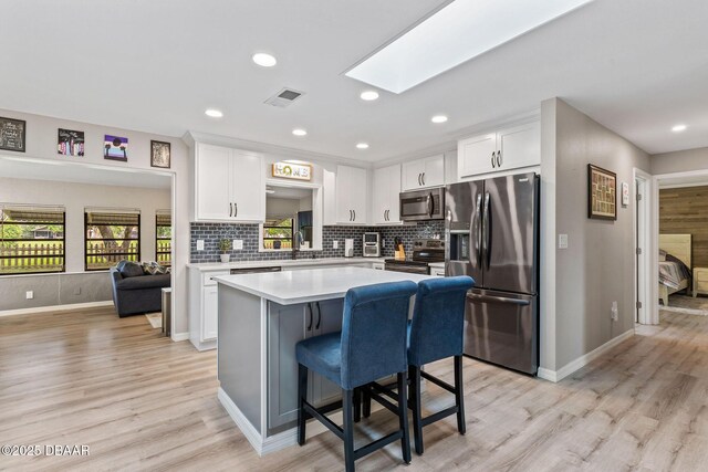 1317 Dexter Dr W, Port Orange, FL 32129 - kitchen with appliances with stainless steel finishes, a kitchen island, white cabinets, light countertops, and baseboards