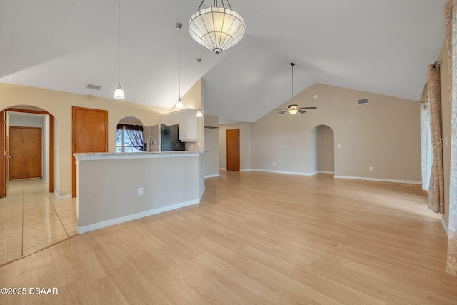 unfurnished living room with ceiling fan, light wood-type flooring, and lofted ceiling