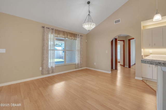 unfurnished dining area with high vaulted ceiling and light hardwood / wood-style flooring