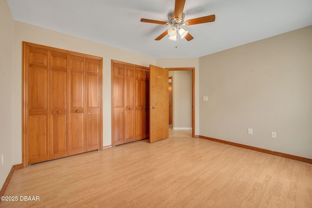 unfurnished bedroom with multiple closets, ceiling fan, and light hardwood / wood-style floors