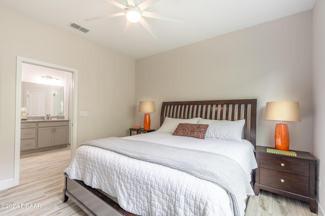 bedroom featuring light hardwood / wood-style floors, ceiling fan, sink, and connected bathroom