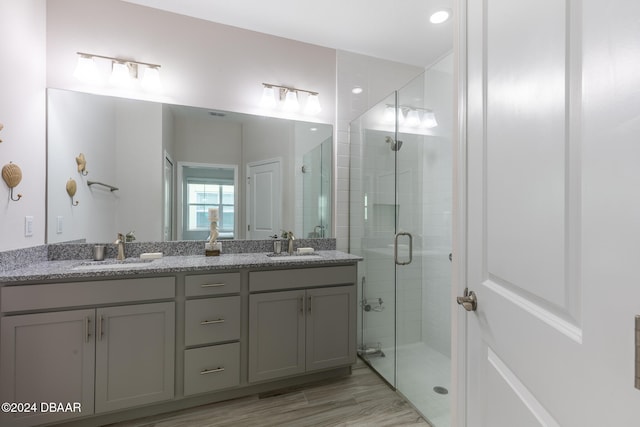 bathroom featuring hardwood / wood-style floors, vanity, and a shower with door