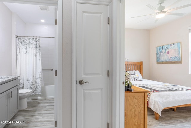 bedroom featuring ceiling fan, ensuite bath, and light wood-type flooring