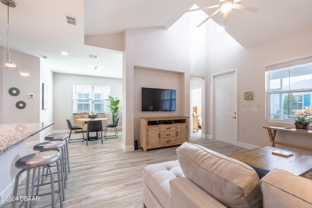 living room with light hardwood / wood-style floors, ceiling fan, and high vaulted ceiling