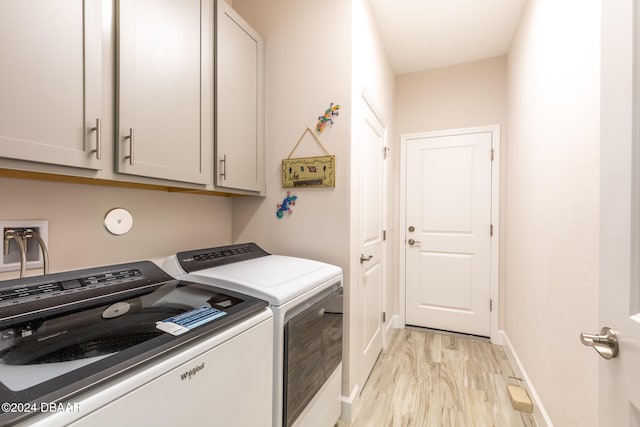 clothes washing area with light wood-type flooring, cabinets, and washer and dryer