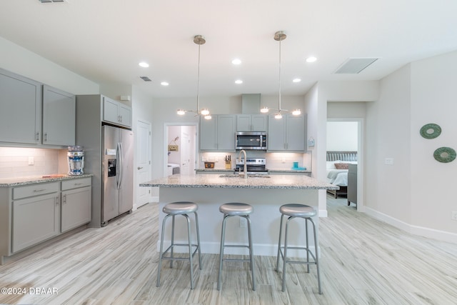 kitchen featuring pendant lighting, light wood-type flooring, appliances with stainless steel finishes, and light stone countertops