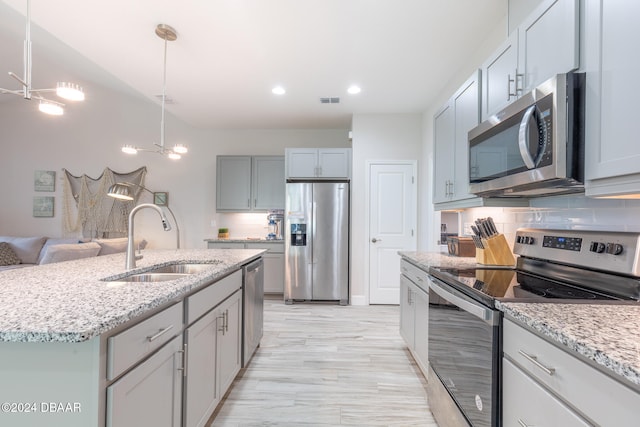 kitchen featuring decorative backsplash, stainless steel appliances, a center island with sink, and sink