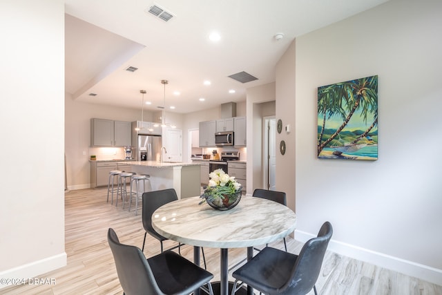 dining area with sink and light hardwood / wood-style flooring