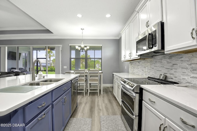 kitchen with blue cabinets, appliances with stainless steel finishes, a sink, white cabinets, and ornamental molding