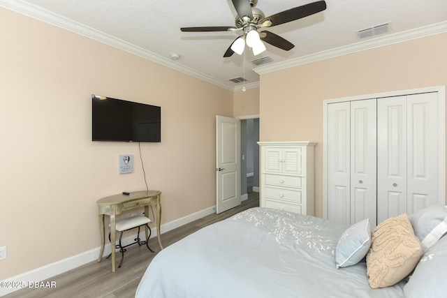 bedroom featuring crown molding, baseboards, wood finished floors, and visible vents