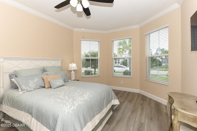 bedroom featuring crown molding, baseboards, ceiling fan, and wood finished floors