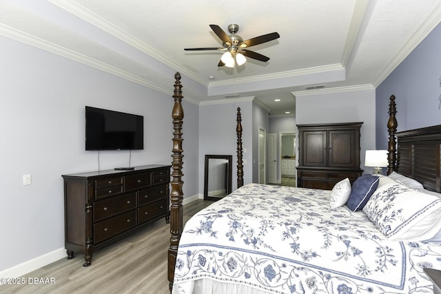 bedroom with crown molding, visible vents, baseboards, light wood-type flooring, and a tray ceiling