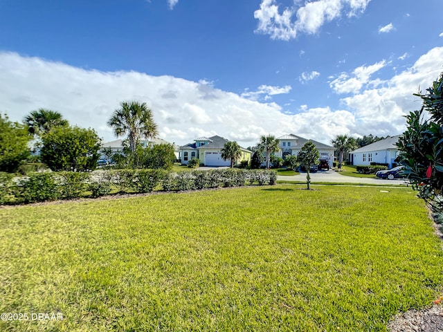 view of yard with a garage, a residential view, and concrete driveway