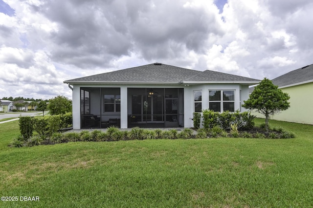 rear view of house featuring roof with shingles, a sunroom, stucco siding, and a yard