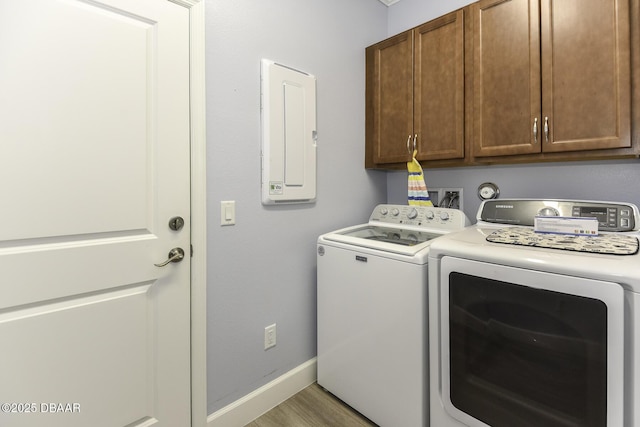 clothes washing area featuring separate washer and dryer, baseboards, light wood finished floors, and cabinet space
