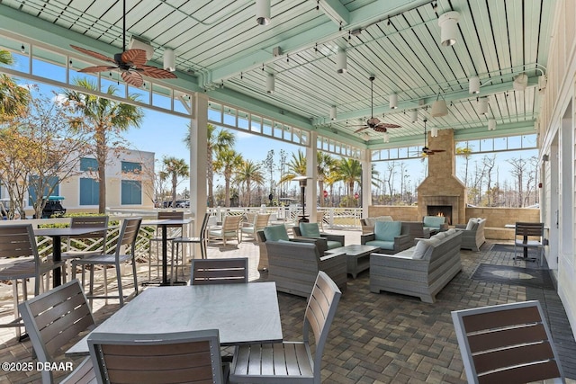 view of patio featuring fence, outdoor dining area, an outdoor living space with a fireplace, and ceiling fan